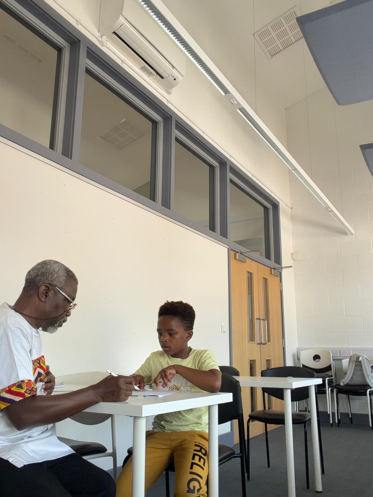 Sylvester Peprah tutoring a young student one-to-one at a desk